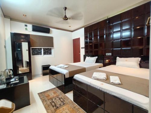 a hotel room with two beds and a mirror at Hotel Joy Guru Inn in Durgāpur