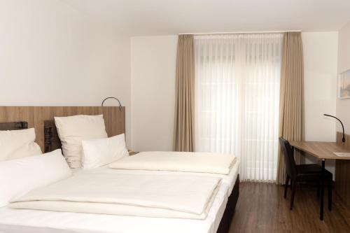 two beds in a room with a table and a desk at Hotel Jesteburger Hof in Jesteburg