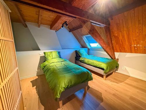 an attic bedroom with two beds and a window at Tussen Muur en Markt in Ieper