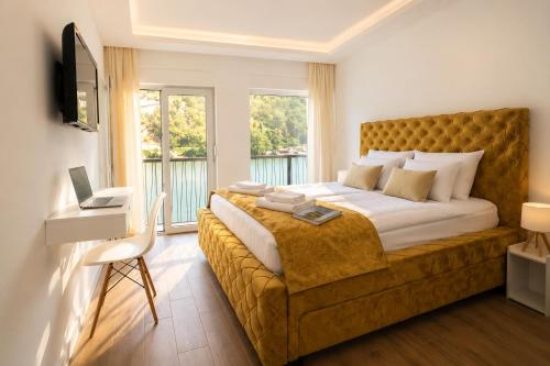 a bedroom with a large bed and a desk with a laptop at Vila Lago Verde in Zvornik