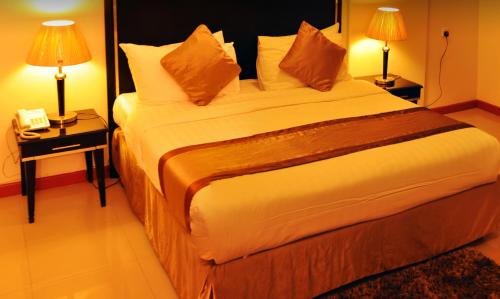 a large bed in a hotel room with two lamps at Nelover Hafar-Serviced apartments in Hafr Al Baten