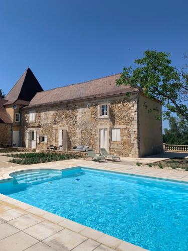 a swimming pool in front of a stone house at B&B Manoir Calmeer in Thenon