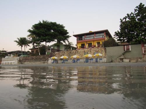 a building with chairs and umbrellas next to the water at Pousada Casa na Praia in Ubatuba