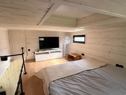 a bedroom with a bed and a flat screen tv at Großzügiges Tiny House in Sumte
