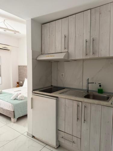a kitchen with white cabinets and a sink and a bed at Zachos studio in Heraklio