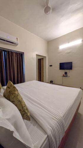 a bedroom with a large white bed with a flat screen tv at Dekatana Hotel Village in Helunmahara