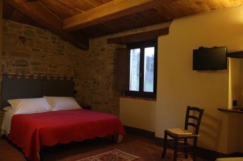 a bedroom with a bed with a red blanket and a tv at Il Gelso Room&breakfast in Pennabilli