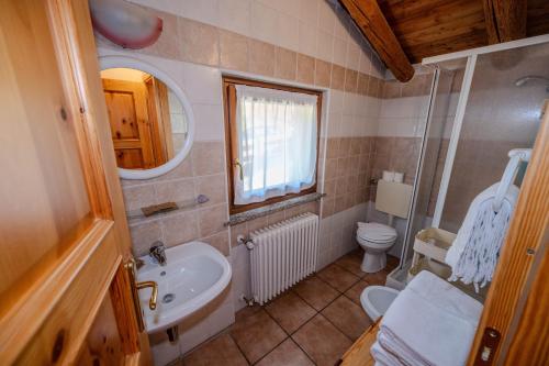 a bathroom with a sink and a toilet and a mirror at Residence Trompe-L'oeil in Champoluc