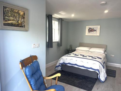 a bedroom with a bed and a blue chair at Ower Retreat in Ower
