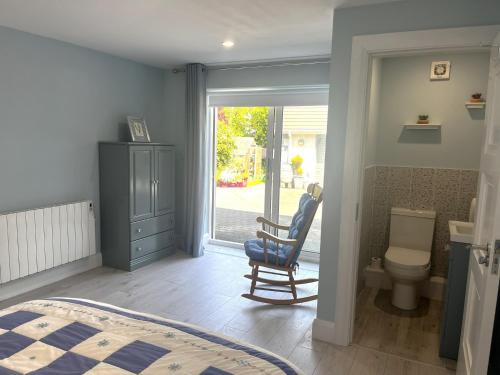 a bedroom with a bed and a chair and a toilet at Ower Retreat in Ower