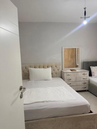 a white bedroom with a bed and a dresser at Bella Vista Apartment in Lezhë
