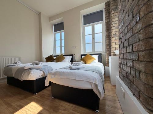 two beds in a bedroom with a brick wall at The Holyrood Mega-Quarters in Edinburgh