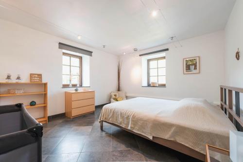 a bedroom with a bed and a dresser and two windows at Une parenthèse en Ardenne in Nollevaux