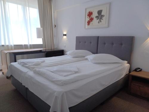 a bedroom with a large bed with white sheets at Hotel Venus in Slănic-Moldova