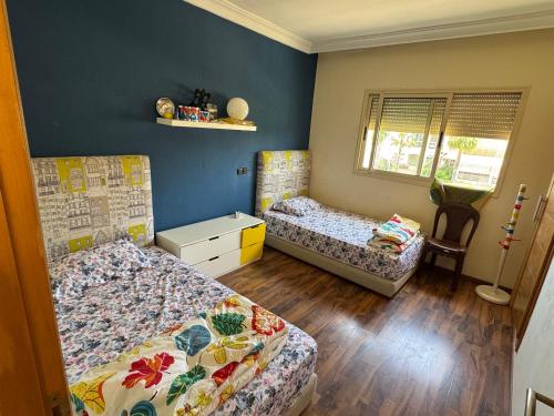 two beds in a room with blue walls and wooden floors at Villa Savannah Beach in Sidi Rahal