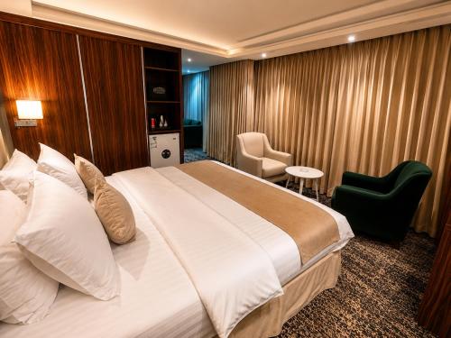 a hotel room with a large bed and a chair at IQ Hotel alhamra فندق اي كيو الحمراء in Jeddah