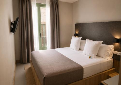 a bedroom with a large white bed with a window at Hotel Casa Gardenia by Blossom Hotels in Barcelona