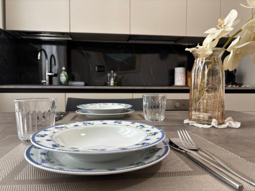 a table with two plates and a vase with flowers at Residenza Vignoli Seregno Centro in Seregno