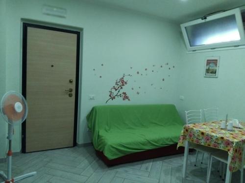 a bedroom with a green bed and a table and a window at APPARTAMENTO in seminterrato PALMAROLA in Sabaudia