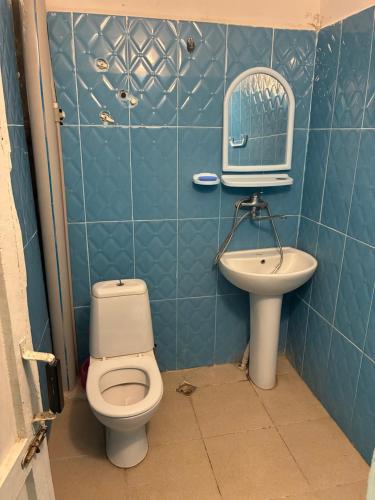 a blue tiled bathroom with a toilet and a sink at Tolia in Ureki