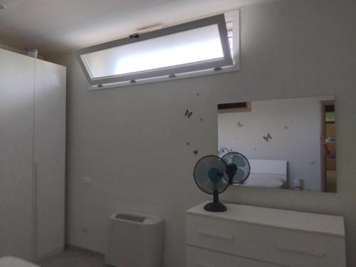 a bathroom with a window and a fan on a dresser at APPARTAMENTO in seminterrato PALMAROLA in Sabaudia