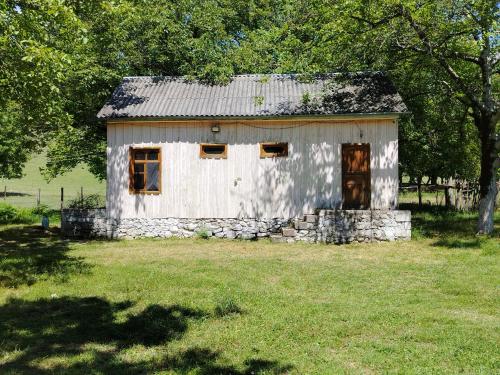 a small white building in a field with trees at Gurbanefendi forest cottages in Qurbanǝfǝndi