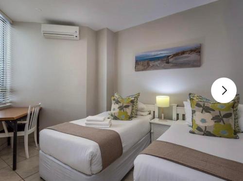 two beds in a room with a table and a desk at 18 Ipanema Beach in Durban