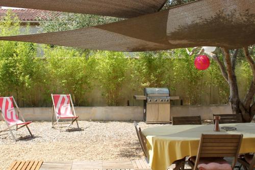 a patio with a table and chairs and a grill at RDC dans maison "ilolil" a 1km plage de la Coudoulière in Six-Fours-les-Plages