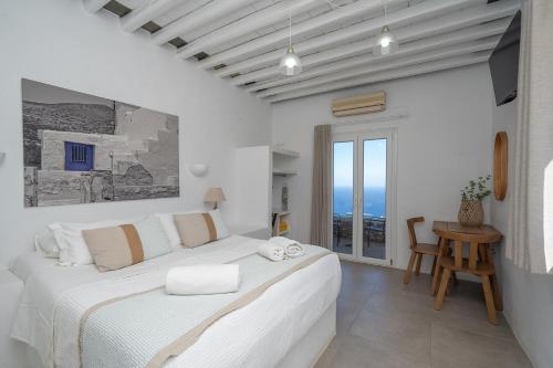 a white bedroom with a large bed and a table at Windmill Bella Vista in Artemonas