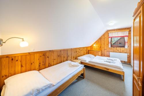 two beds in a room with wooden walls at Chalupy Na Rališce in Horní Bečva