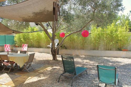 a patio with a table and chairs under a tree at RDC dans maison "ilolil" a 1km plage de la Coudoulière in Six-Fours-les-Plages