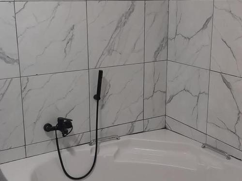 a shower with a hose attached to a tiled wall at Harnham Mountain Lodge in Elsteg