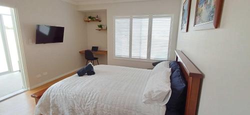 a bedroom with a bed and a desk and a television at Cosy Haven - Large Comfy Dwelling in Mandurah