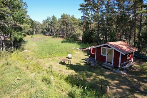 a small red cabin in the middle of a field at Dunderfriggan på Möja in Möja