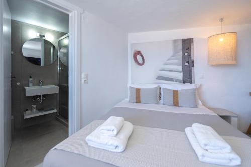a white bedroom with a bed with towels on it at Windmill Bella Vista in Artemonas
