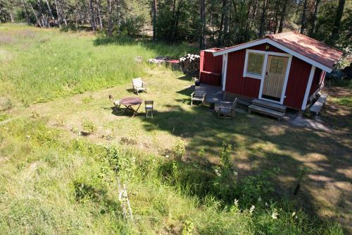 a small red cabin in a field with chairs at Dunderfriggan på Möja in Möja