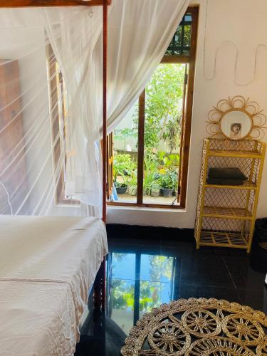 a bedroom with a bed and a large window at ThePopos in Arugam Bay