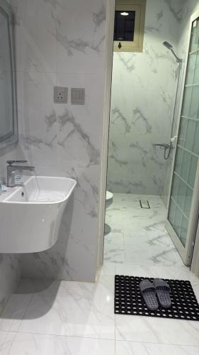 a white bathroom with a sink and a shower at شقق نطوان المفروشة in Abha