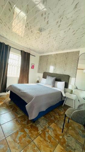a bedroom with a large bed and a chair at Mukomani Guesthouse in Soshanguve