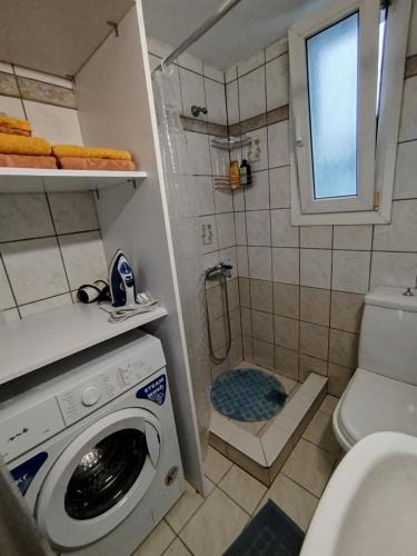 a bathroom with a washing machine and a shower at DiPo's Beachside House with Sea View in Samos