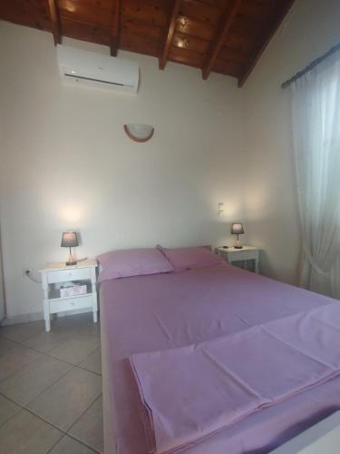 a bedroom with a purple bed and two tables at DiPo's Beachside House with Sea View in Samos