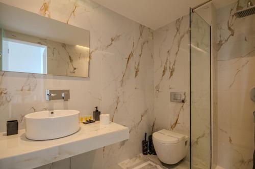 a bathroom with a sink and a toilet and a mirror at Alyssium in Benitses
