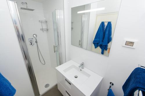 a white bathroom with a sink and a shower at Apartment Noemi in Rovinj