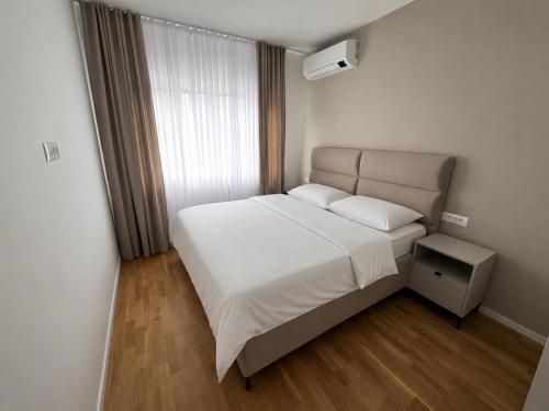 a small bedroom with a white bed and a window at NOVA Olimpia Residence - Free Garage in Sarajevo
