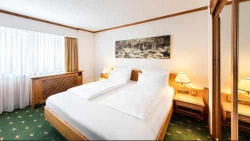 a hotel room with a large bed and a window at Sonnenhof Resort Himmelreich Bayerischer Wald in Lam