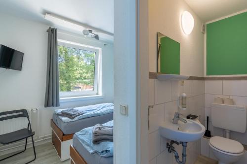 a bathroom with a sink and a toilet and a bed at Flensbed Hotel & Hostel in Flensburg