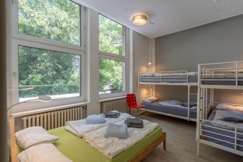 a bedroom with two bunk beds and a red chair at Flensbed Hotel & Hostel in Flensburg