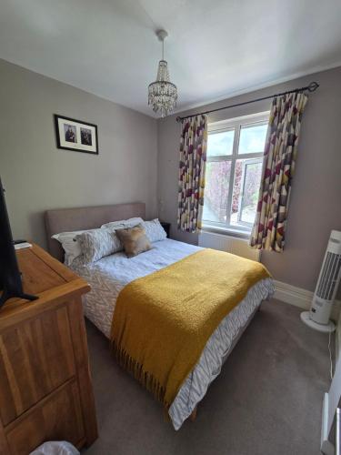 a bedroom with a bed with a yellow blanket and a window at The Homestay in High Wycombe