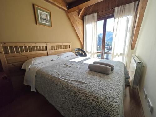 a bedroom with a bed and a large window at Los Altos de Escarrilla - tucasaenlospirineos in Escarrilla