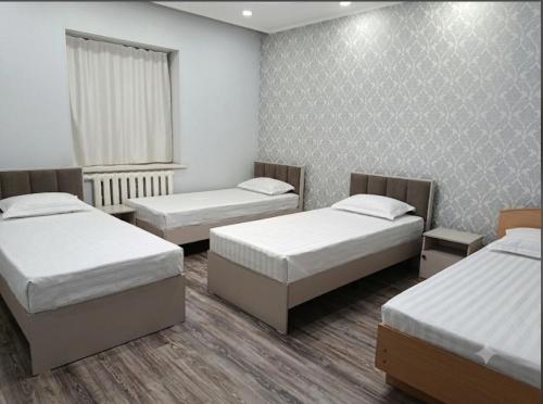 a room with three beds and a window at BoNa Guest in Bishkek